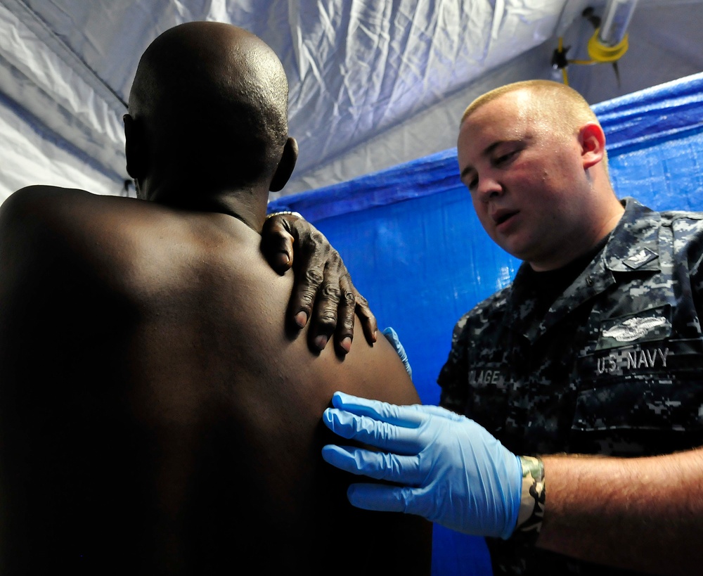Petty Officer 3rd Class Ian Polage, hospital corpsman, assigned to Naval Medical Center San Diego, checks a shoulder injury on Edward Patterson, a Marine Corps veteran, during triage inside the Veteran's Village of San Diego Stand Down 2010 medical tent.