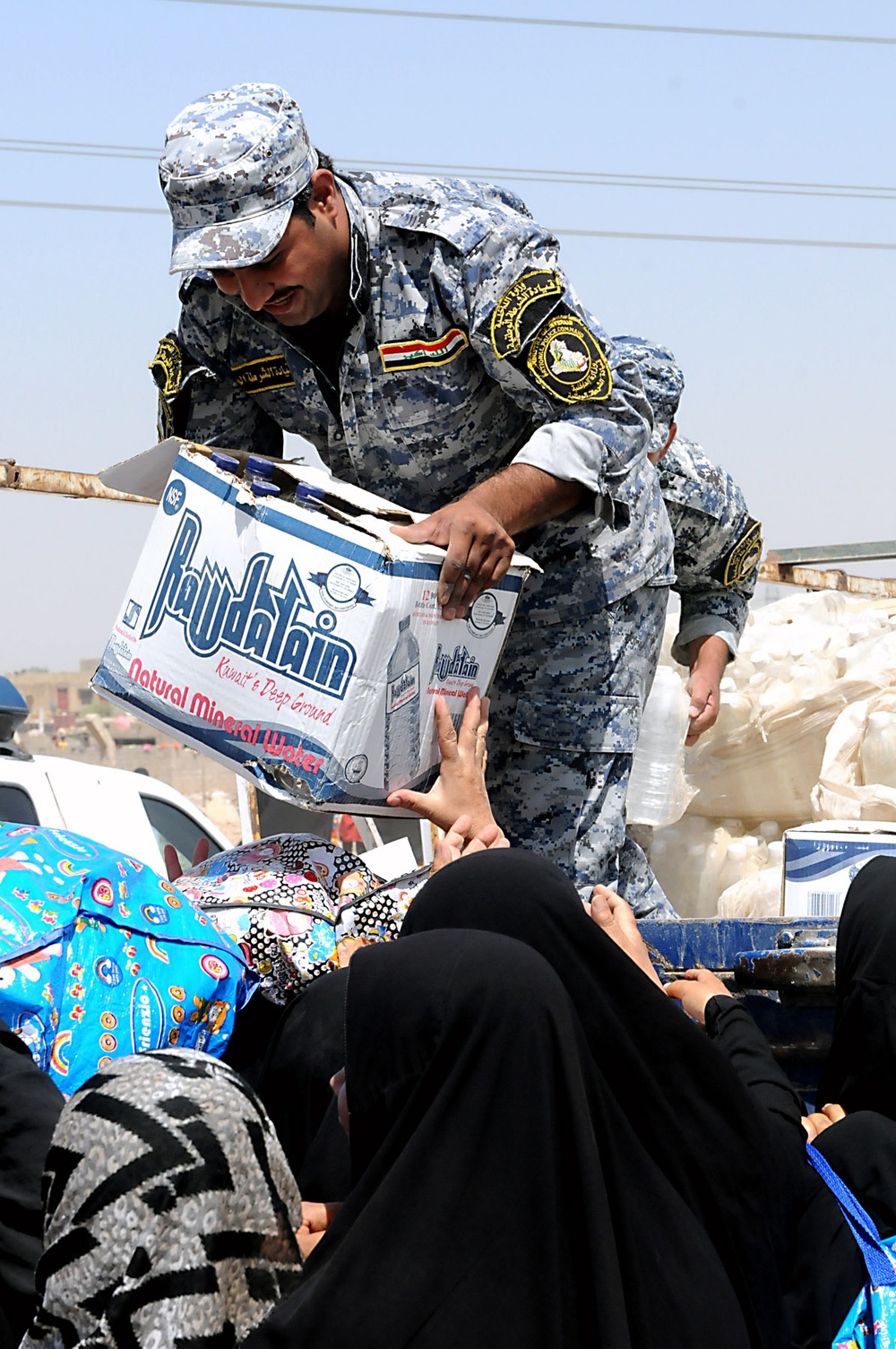 Artillerymen, policemen find thankful crowd during aid mission
A sergeant with the 1st Federal Police passes a box of bottled water to a group of Iraqi women during a humanitarian aid mission in northeastern Baghdad, July 17. In accordance with the Securi