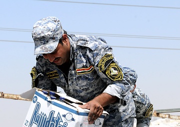 Artillerymen, policemen find thankful crowd during aid mission
A sergeant with the 1st Federal Police passes a box of bottled water to a group of Iraqi women during a humanitarian aid mission in northeastern Baghdad, July 17. In accordance with the Securi