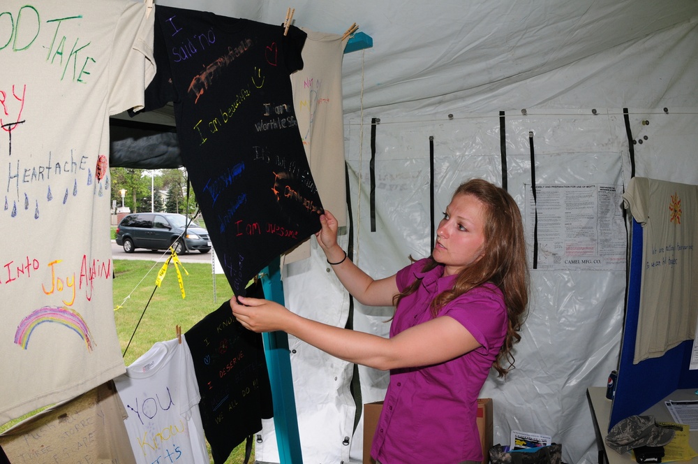 Staff Sgt. Heather Prigge, of the 119th Wing, talks about a t-shirt on a clothesline project display, July 29, on the Fargo, N.D. Veteran's Administration Hospital grounds. The Clothesline Project display is using t-shirts created by victims of military s