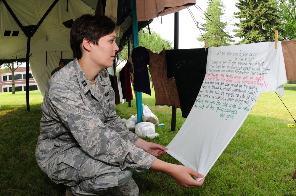 Capt. Penny Ripperger, the 119th Wing sexual assault response coordinator, reads a poem written on a t-shirt July 28, at a Clothesline Project visual display on the Veteran's Administration Hospital grounds, Fargo, N.D. The Clothesline Project display USE