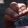 A close-up photograph of a person's hands handling what appears to be a firearm magazine with a bullet/cartridge visible. The image is tightly cropped, focusing on the hands and the dark metallic object. The green-tipped bullet is clearly visible being loaded or handled at the top of the magazine.