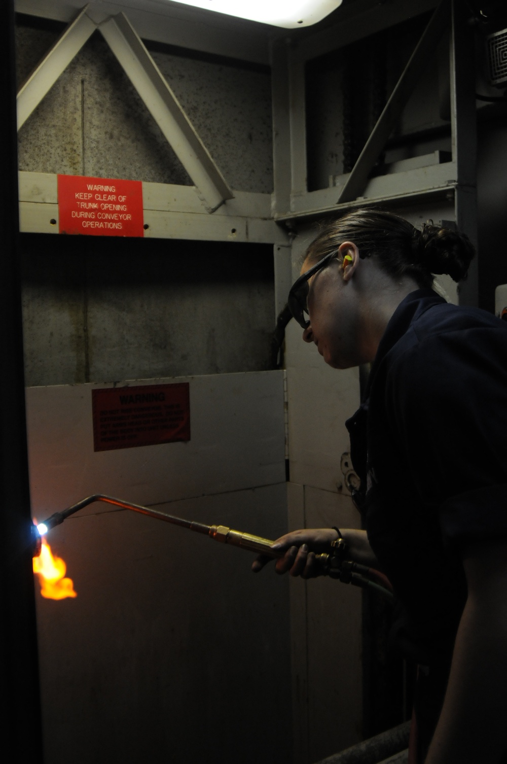 USS Wasp sailors repair a vertical conveyor