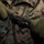 1/1 Marines Begin Exercise Mountain Warrior at Bridgeport A close-up image showing gloved hands working with a dark braided rope or cord, likely tying a knot. The individual is wearing United States Marine Corps MARPAT (Marine Pattern) woodland digital camouflage uniform. Olive drab knit gloves are visible on both hands.