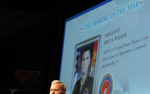 A senior U.S. Marine Corps officer in dress blues stands at a USO-branded podium during the 2010 USO Gala. He is presenting the 'USO Marine of the Year' award, with a projection screen behind him displaying the honoree: Sergeant Eric B. Walker of MARSOC (Marine Corps Forces Special Operations Command), Jacksonville, NC. The event appears to be a formal military awards ceremony.