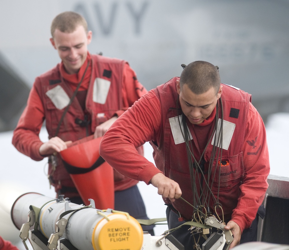 Sailors move aircraft weapons
