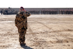 A German officer salutes during the German National Anthem at a TF Kunduz change of command