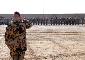 A German officer salutes during the German National Anthem at a TF Kunduz change of command
