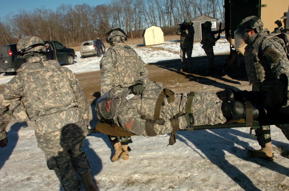 New Mexico National Guard medics carry simulated injured soldier during riot control exercise