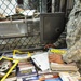 A detainee looks through a book offered to him from a Soldier from the detainee library in Camp Five