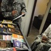 A soldier from the detainee library reviews a book record before offering books to a detainee in Camp Five