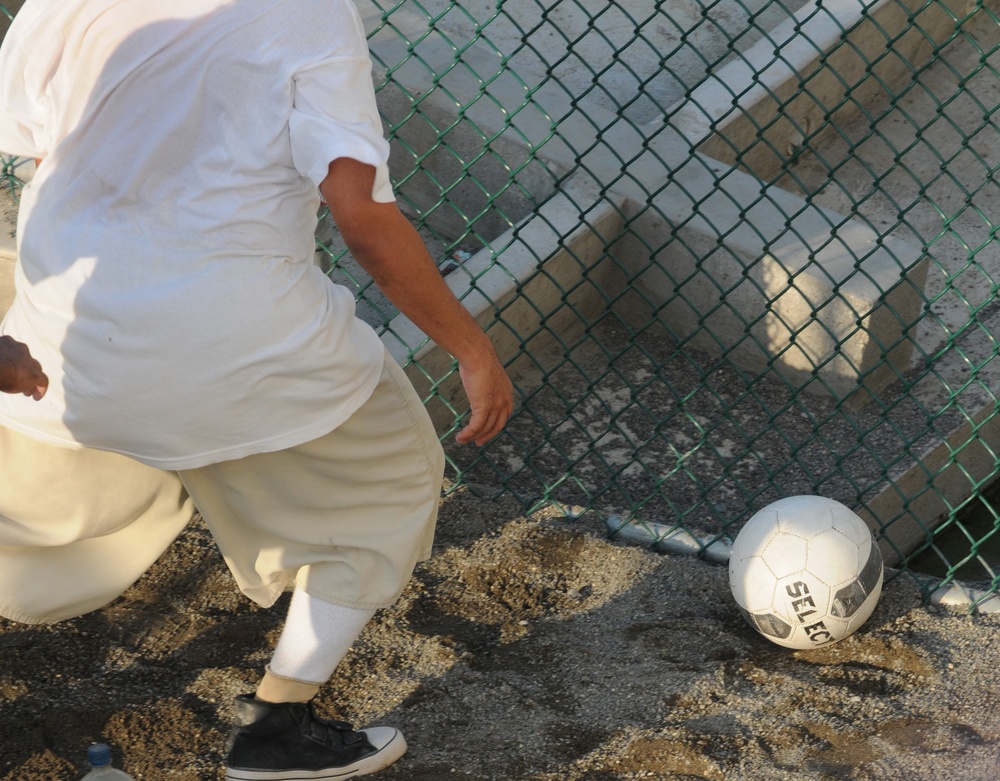 A detainee goes after a soccer ball within the outdoor recreation area of Camp Six at Joint Task Force Guantanamo