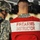 432nd CA BN prepares for deployment to Afghanistan Two individuals in U.S. Army camouflage uniforms (ACU pattern) are photographed from behind at what appears to be a firing range. The person in the foreground is wearing a red and white vest clearly labeled 'FIREARMS INSTRUCTOR' and black ear protection headset. The person to the left is wearing a combat helmet and appears to be a trainee or student at the range.