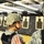 432nd CA BN prepares for deployment to Afghanistan Two U.S. Army soldiers in ACU (Army Combat Uniform) pattern camouflage are at an indoor shooting range. Both wear ballistic helmets and body armor. One soldier, a female, is being coached or guided by another soldier, with shooting targets visible in the background.