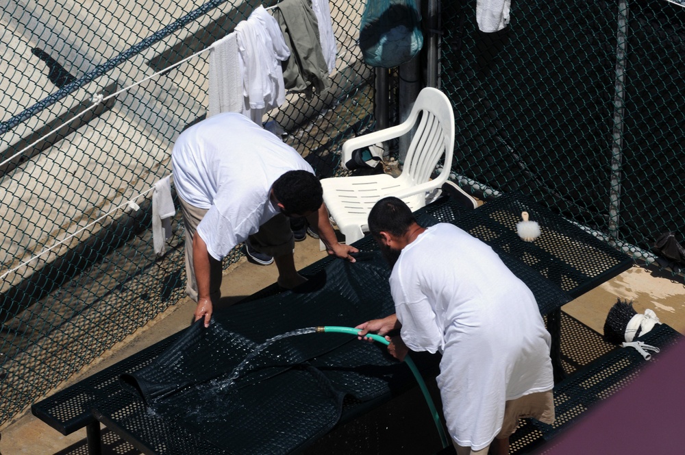 Two detainees wash a mat in the outdoor recreation area of Camp Six at Joint Task Force Guantanamo