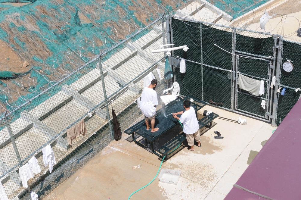 Two detainees wash a mat in the outdoor recreation area of Camp Six at Joint Task Force Guantanamo