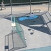 A detainee relaxes in the outdoor recreation area of Camp Six at Joint Task Force Guantanamo as a guard walks by