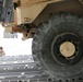 As a truck is moved into a C-17 aircraft, a Seabee signals to the loadmaster