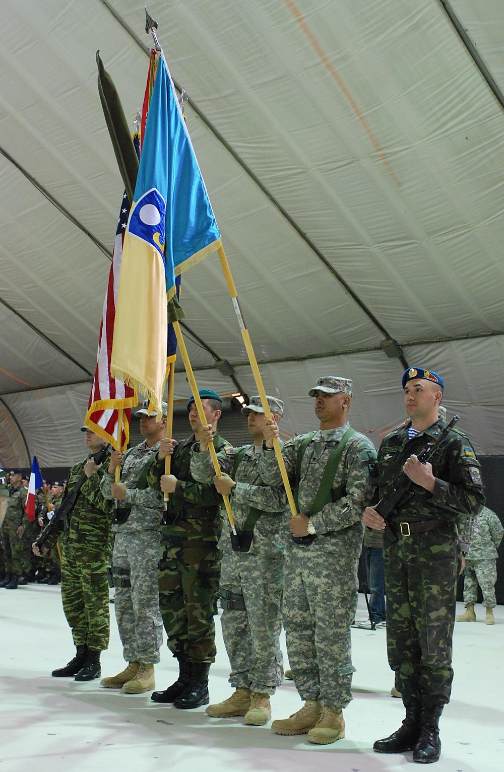 Multinational soldiers present arms during transfer of authority ceremony