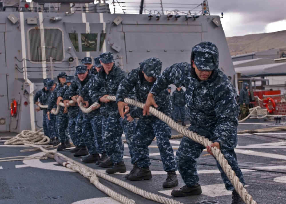 Sailors take in the aft storm line as USS Forrest Sherman gets underway.