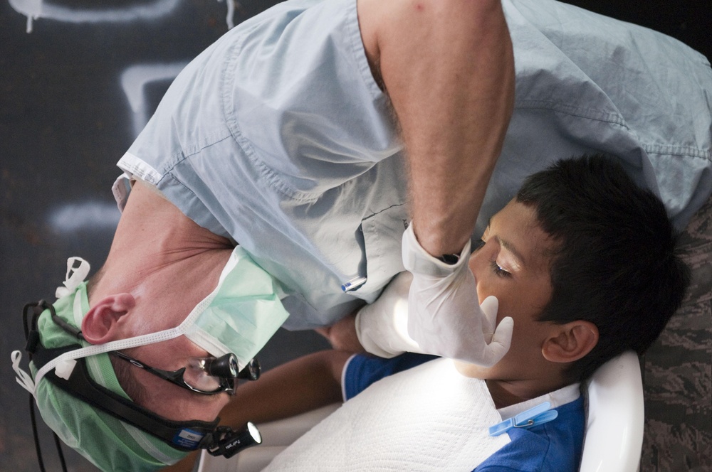Air Force dentist checks Salvadoran child for cavities during humanitarian mission