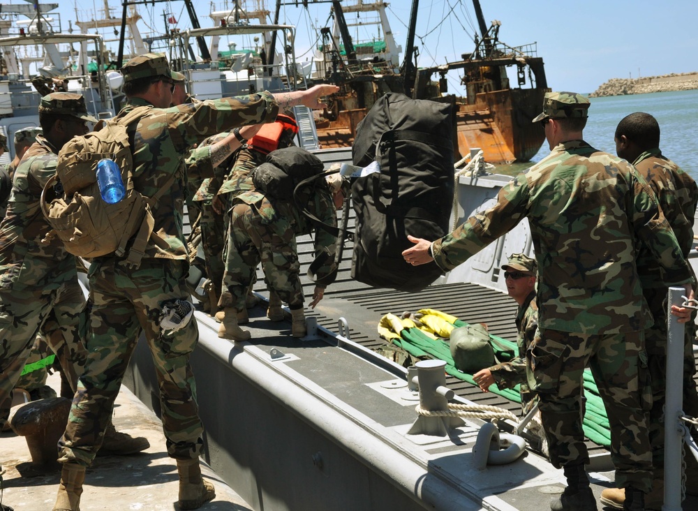 Sailors load equipment onto a LCM8 naval vessel