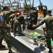 Sailors load equipment onto a LCM8 naval vessel