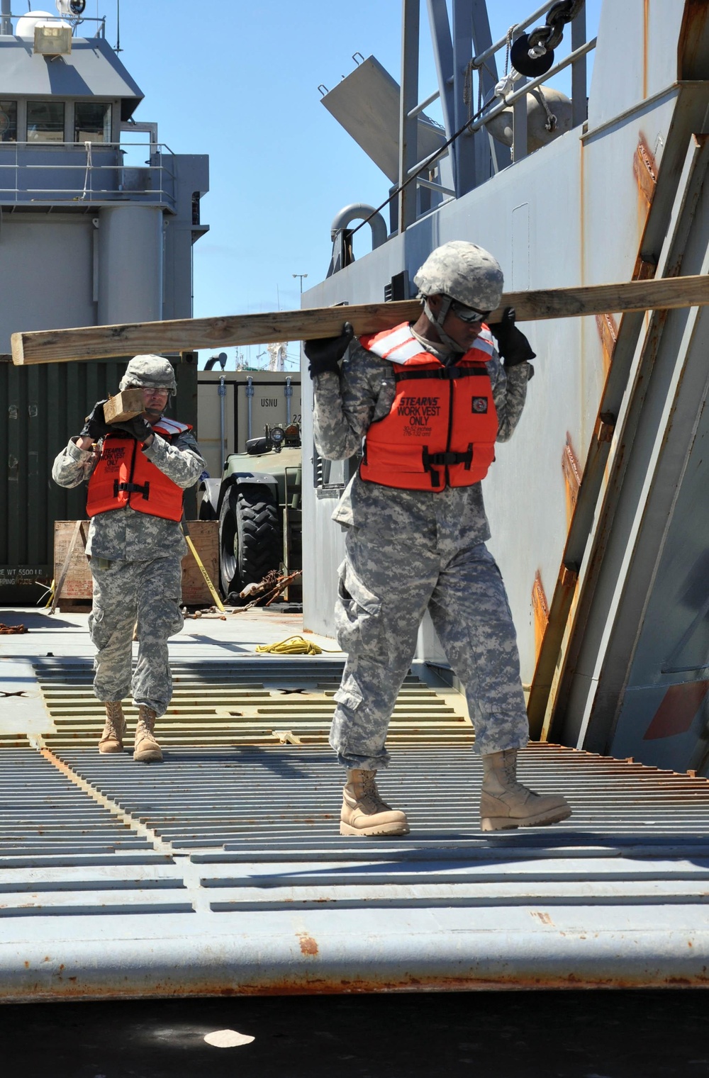 Soldiers unload wood off of Army vessel