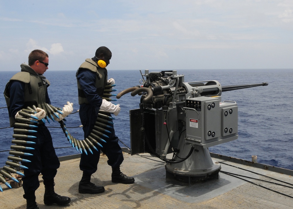 USS Frank Cable sailors load rounds into machine gun