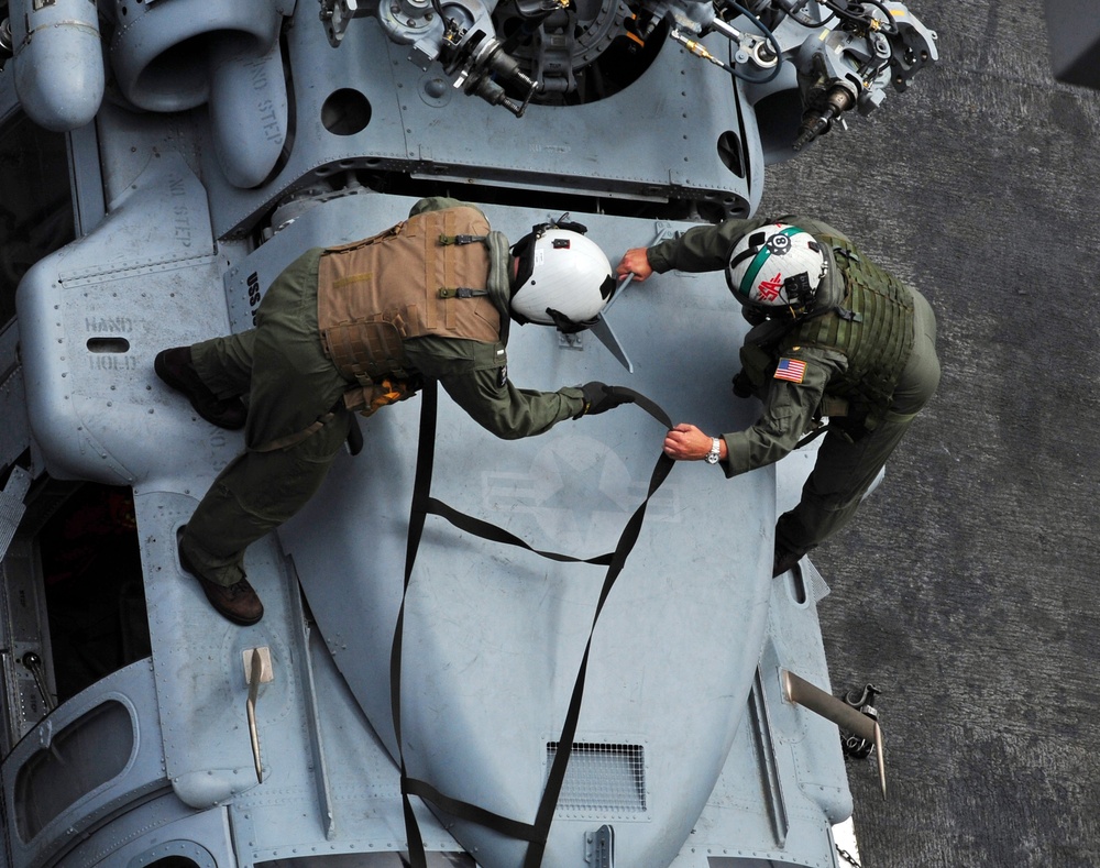 USS John C. Stennis sailors adjust straps on MH-60S Sea Hawk