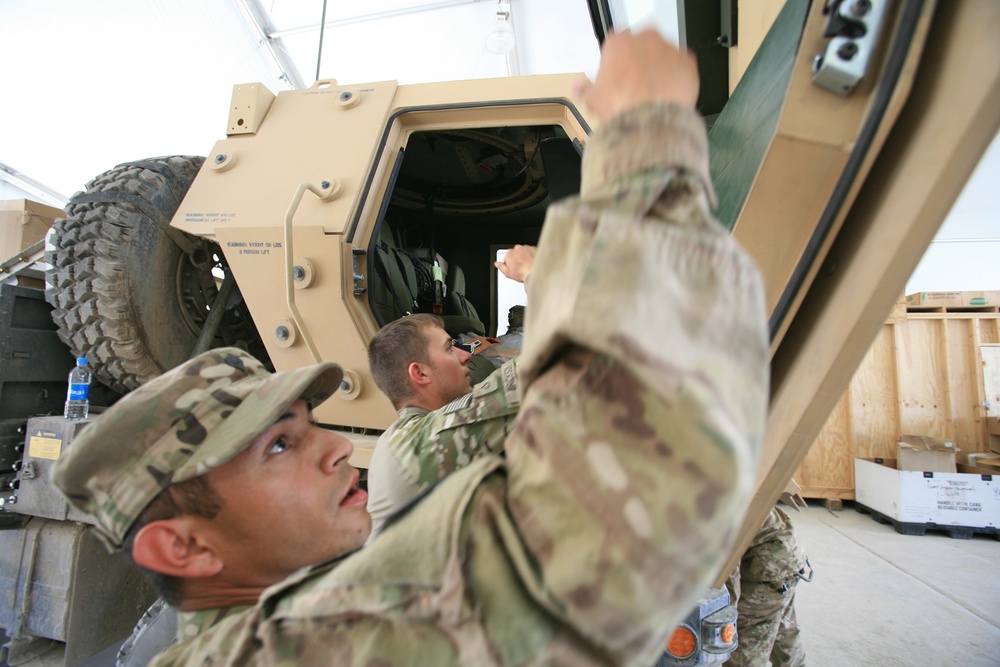 Soldiers fix a door on a vehicle