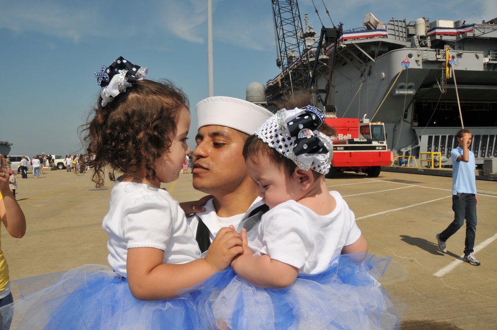 Seaman Jonathan Vargas holds his daughters during the amphibious assault ship USS Kearsarge return to Naval Station Norfolk