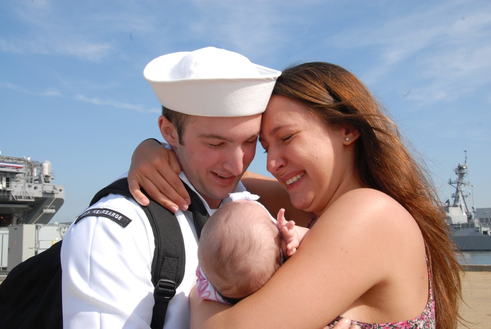 Seaman Roberto Valentine holds his daughter for the first time during the amphibious assault ship USS Kearsarge return to Naval Station Norfolk