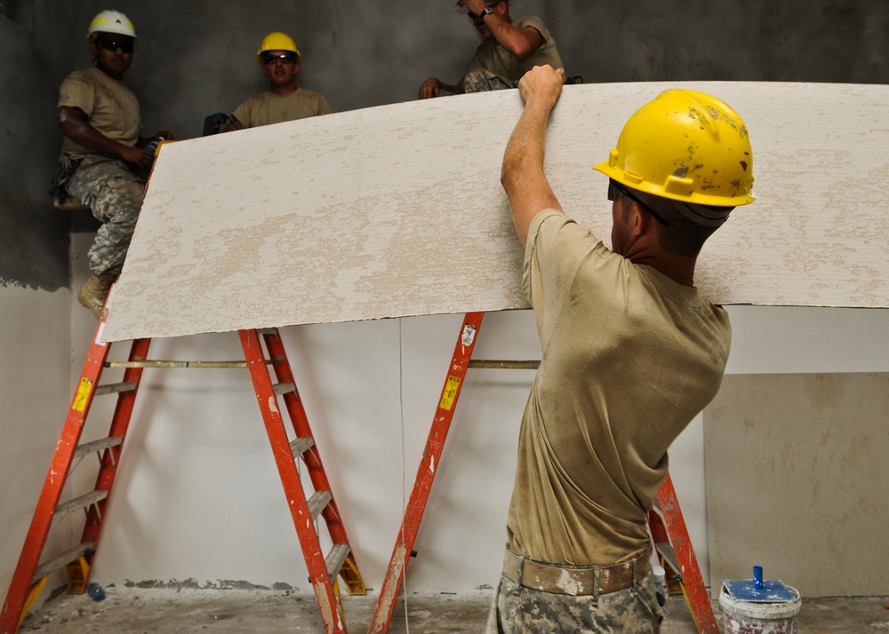 Soldiers place gypsum board on school wall in Cambodia