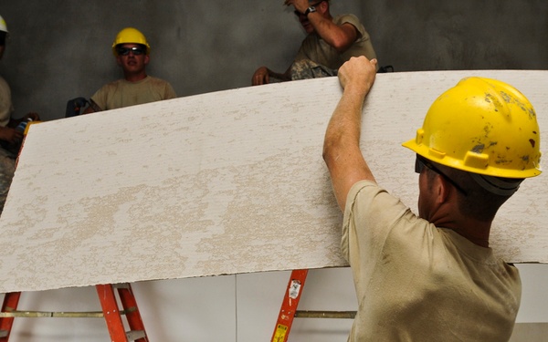 Soldiers place gypsum board on school wall in Cambodia