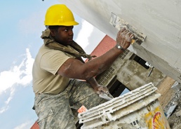 US Soldier applies plaster to latrine wall