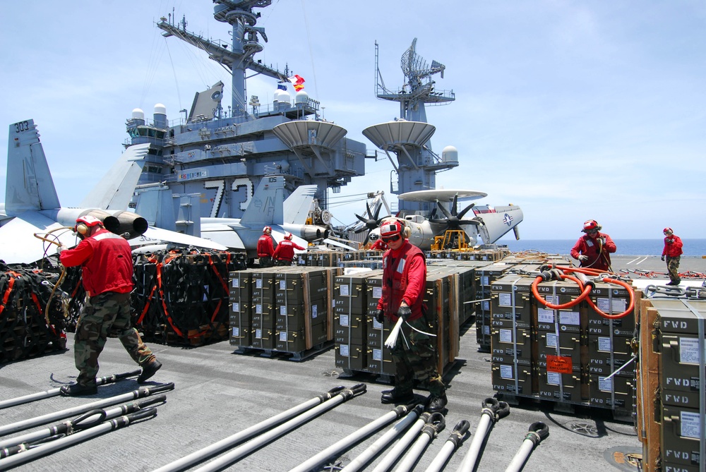 Sailors aboard USS George Washington's flight deck prepare ordnance containers