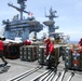 Sailors aboard USS George Washington's flight deck prepare ordnance containers