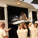 Military personnel in US Air Force uniforms (ABU/ACU pattern) are loading or unloading a patient on a stretcher/litter through the open side door of a white bus or transport vehicle. At least three uniformed service members outside are lifting the stretcher upward while individuals inside the vehicle assist in receiving it. The scene appears to be a medical evacuation or patient transfer operation.