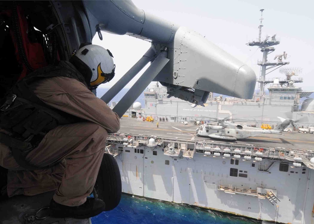 Sailor watches as MH-60 Sea Hawk lands aboard USS Bataan