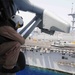 Sailor watches as MH-60 Sea Hawk lands aboard USS Bataan