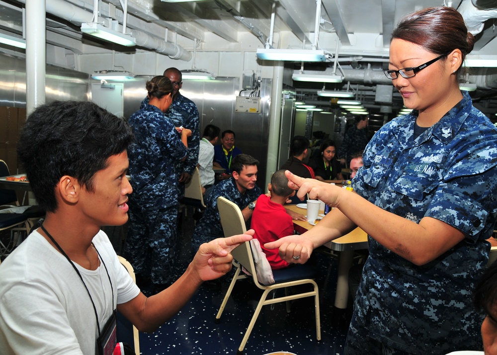 USS Frank Cable sailors sign with children during tour