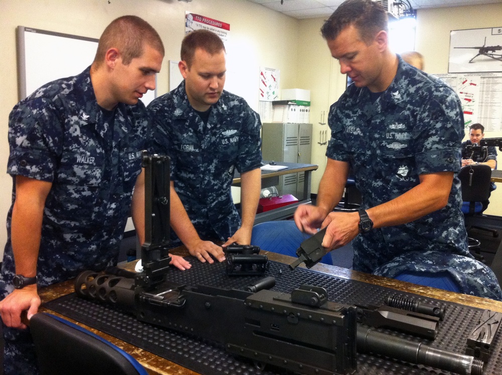 ailor demonstrates how to disassemble a machine gun