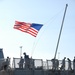 Sailors aboard the Arleigh Burke-class guided-missile destroyer USS Mason (DDG 87) lower the national ensign as they depart Naval Station Norfolk in advance of Hurricane Irene