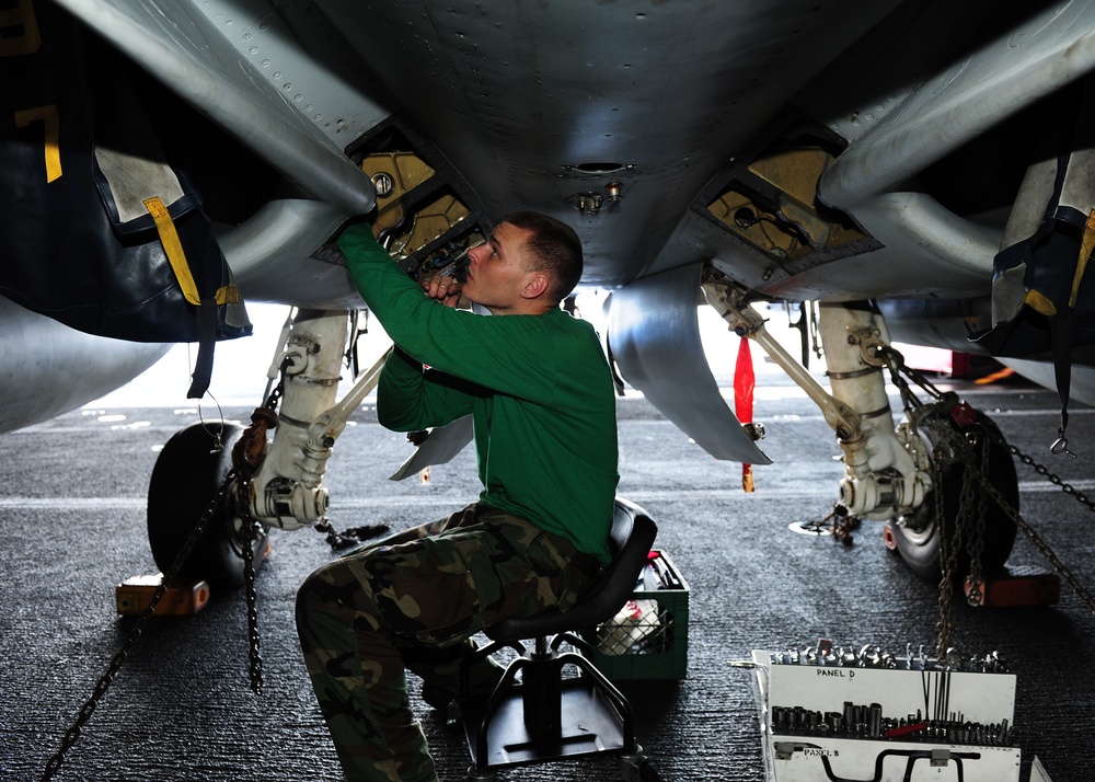 Sailor cleans out debris under F/A-18C Hornet