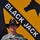 A U.S. Army soldier wearing ACU (Army Combat Uniform) stands in front of a large painted mural of the 1st Cavalry Division 'Black Jack' insignia. The soldier is identified by name tape as 'AVENT' and wears a major's oak leaf cluster insignia along with a cavalry Stetson hat. The background mural features the distinctive yellow and black shield of the 1st Cavalry Division with the text 'BLACK JACK'.
