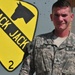 Soldier stands in front of unit crest while serving on a deployment to Iraq