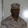 A U.S. Marine in desert MARPAT (Marine Pattern) camouflage uniform is photographed in what appears to be an indoor setting against a white wall. The name tape reads 'JOHNSON' and the branch tape reads 'U.S. MARINES'. The subject is wearing a cover (cap) with the Eagle, Globe, and Anchor emblem visible.