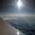 New SACEUR makes first visit to Kosovo A photograph taken from inside a commercial aircraft looking out over the wing toward a vast cloudscape below. The sun is positioned high in the frame, creating significant lens flare and glare across the image. Scattered cumulus clouds are visible below the aircraft against a hazy horizon.