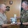 New SACEUR makes first visit to Kosovo Two military officers are exchanging a commemorative plaque in what appears to be an official ceremony. The officer on the left wears a US Navy/Marine Corps tan uniform with four-star rank insignia, while the officer on the right wears a camouflage uniform with a NATO patch and a name tag reading 'GAY'. The plaque features a NATO emblem and appears to be a formal gift exchange between allied military commanders.